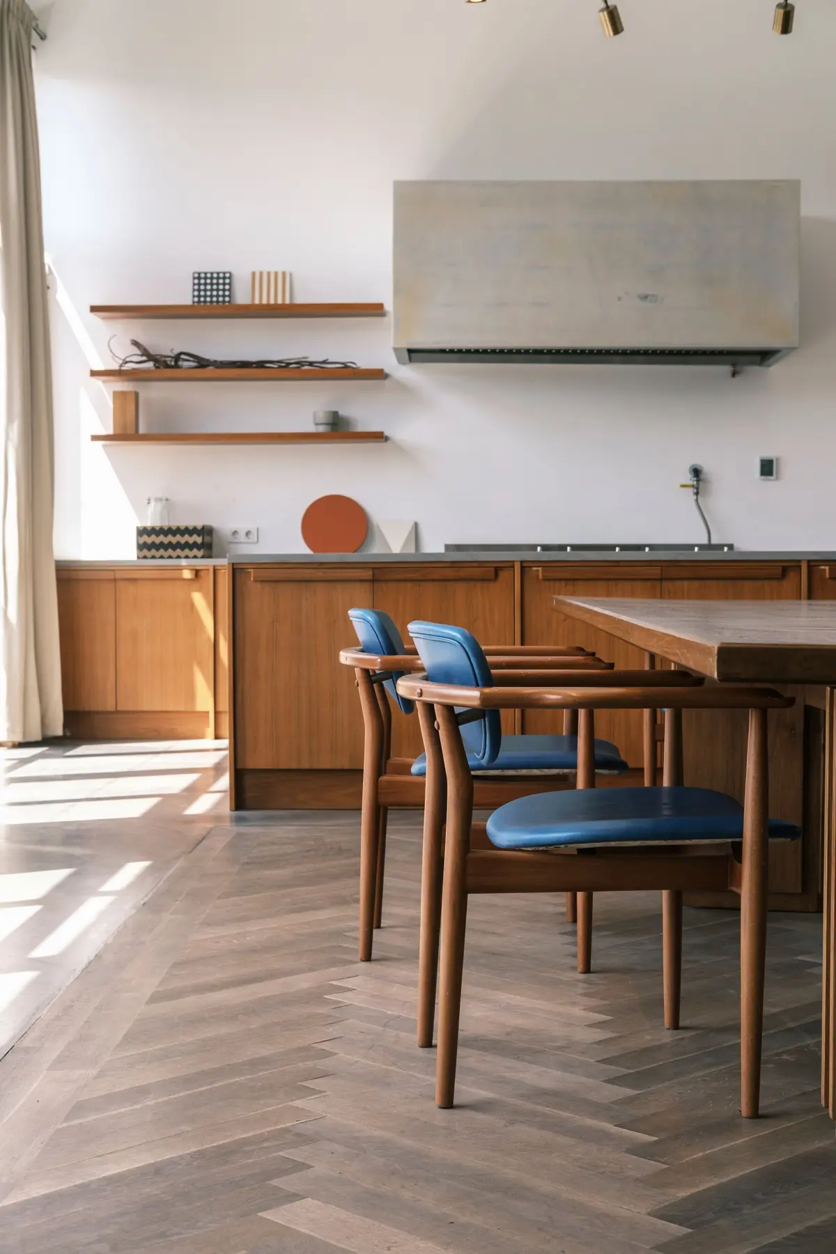 Keuken met houten tafel, blauwe stoelen en warme houtlook vloer